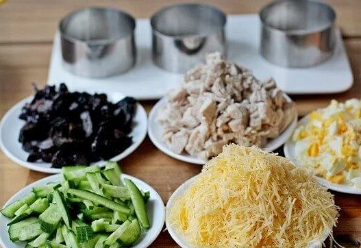 Продукты для приготовления салата с курицей, черносливом, рисом и огурцами на столе
